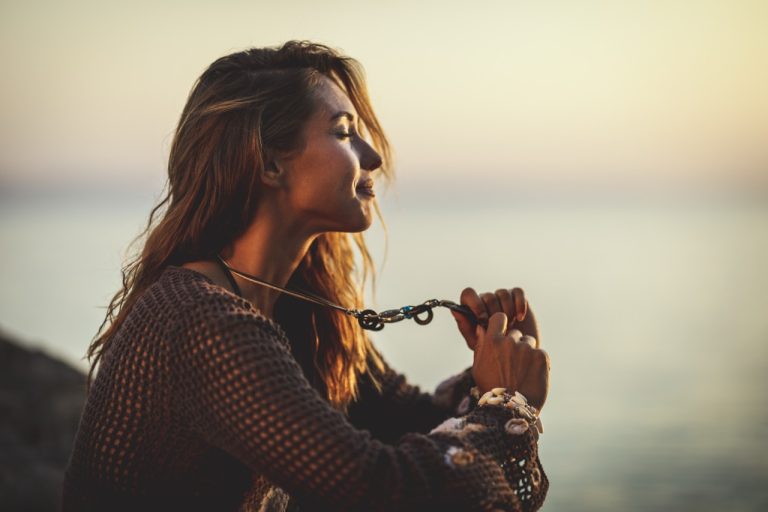 A beautiful young woman is relaxing on the beach at the sunset.