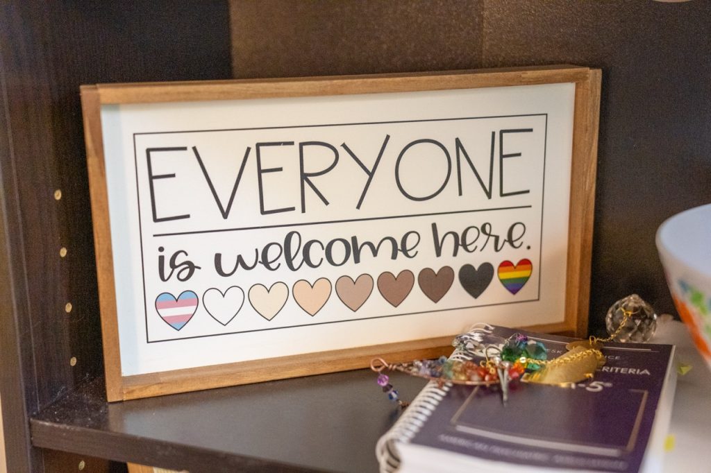 A framed, inclusive art piece reading "EVERYONE is welcome here" displayed on a desk in the reception area of River's Bend, P.C.