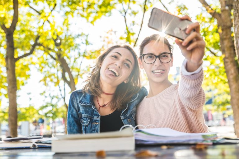 Two students taking a selfie outdoors during back to school season in Michigan.