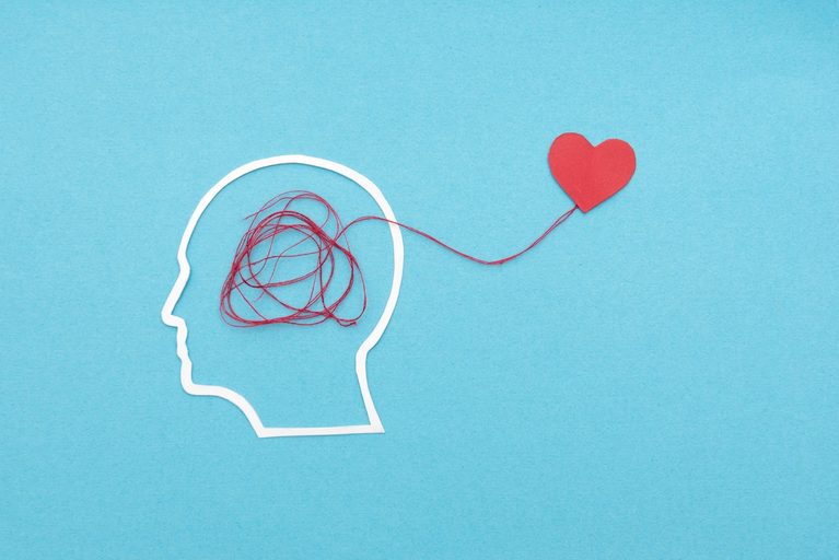 Silhouette profile with a red thread connecting brain to heart, symbolizing mental and emotional health care.