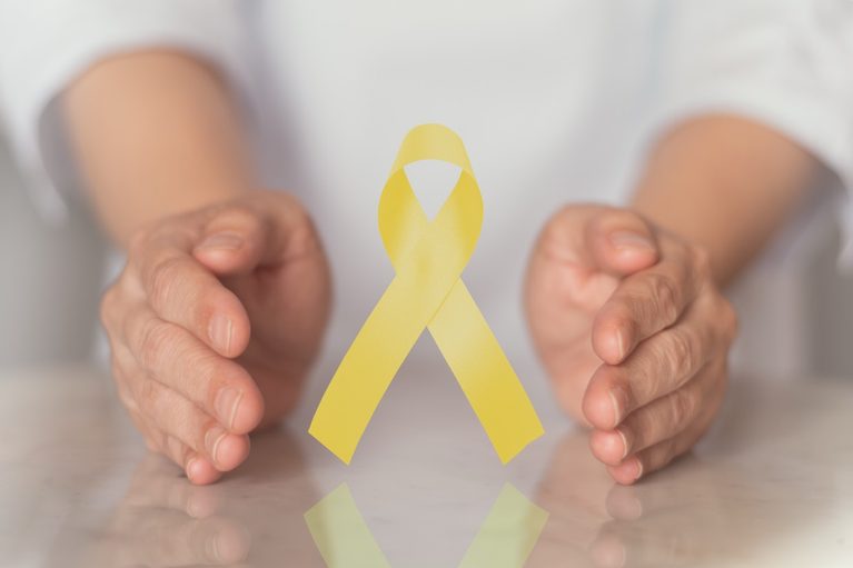 Two hands gently cradling a yellow ribbon, the symbol for suicide prevention awareness.